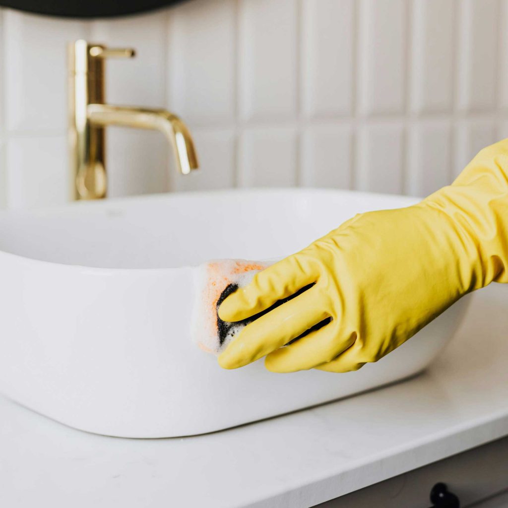 Čištění umyvadla v koupelně rukavicí