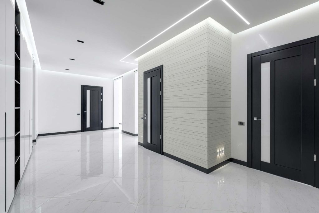 Moderní světlá chodba s lesklou podlahou a tmavými dveřmi