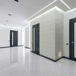 Moderní světlá chodba s lesklou podlahou a tmavými dveřmi