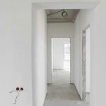 rázdná bílá chodba po stavbě s otevřenými dveřními otvory