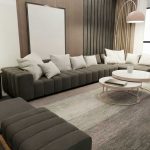 Elegantní obývací nebo čekací prostor s pohovkou, stolky a polštáři.